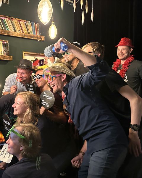 The team crowded into a photo booth with props, everyone laughing