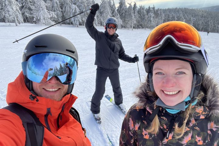 Three of the team on the piste, snow-covered pines behind them