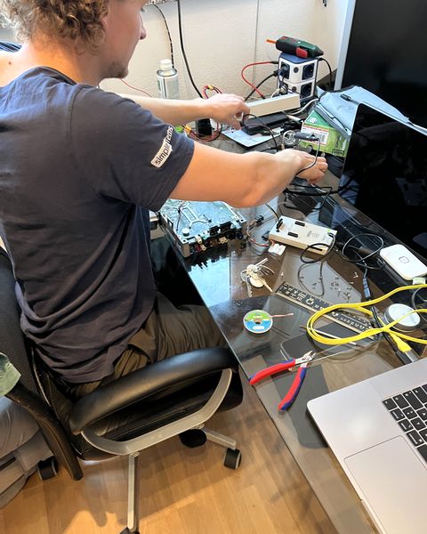 A colleague at a desk with a circuit board taken apart in front of him